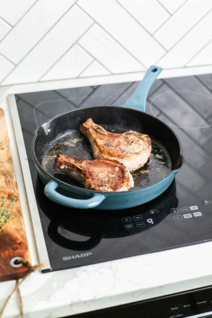 Pork chops being seared in a pan on a Sharp Induction Cooktop SCH3043GB