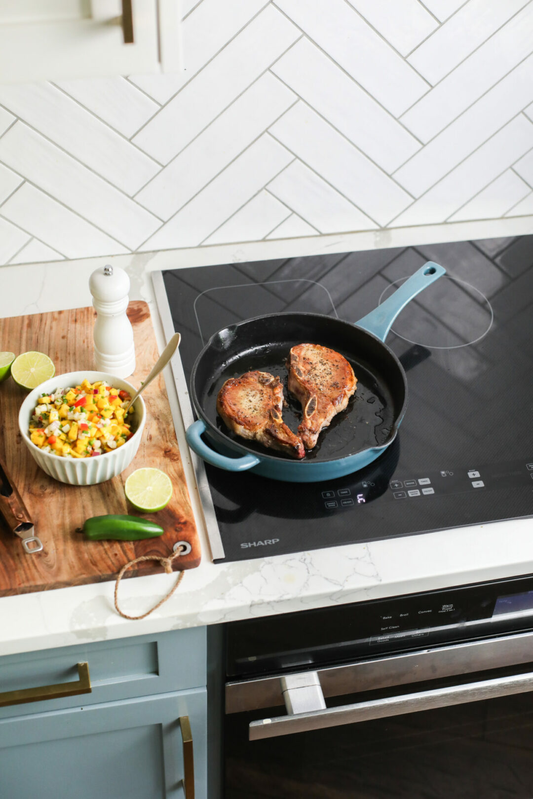 Pork chops in a blue skillet atop a Sharp 30 in. Induction Cooktop with Side Accessories (SCH3043GB)