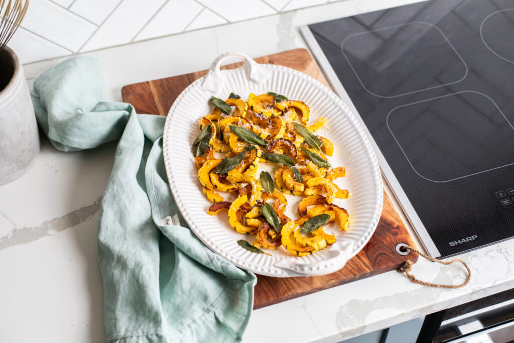 Delicata squash with sage on a serving platter next to a Sharp Induction Cooktop