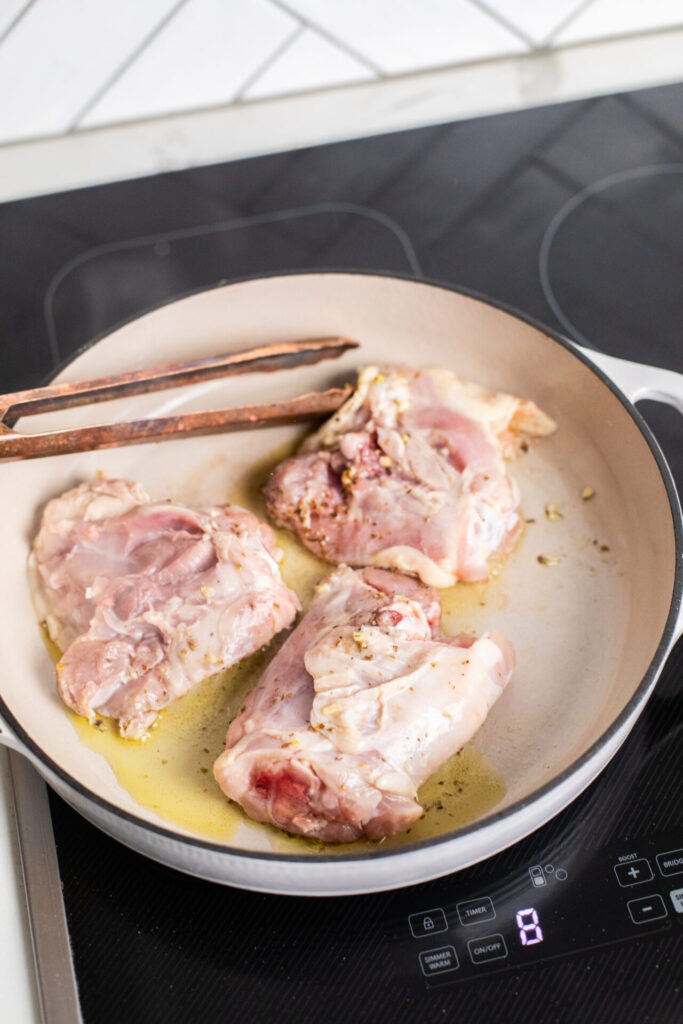 Seasoned chicken thighs in a pan on a Sharp Induction cooktop