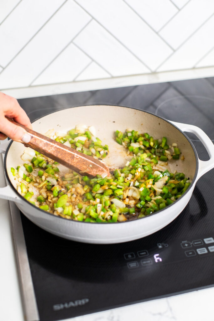 Onions and green peppers being sautéed over medium high heat on a sharp induction cooktop