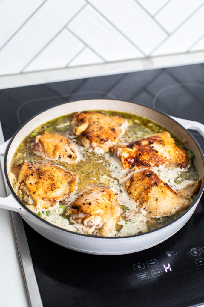 Chicken cooking in a pan on a sharp cooktop