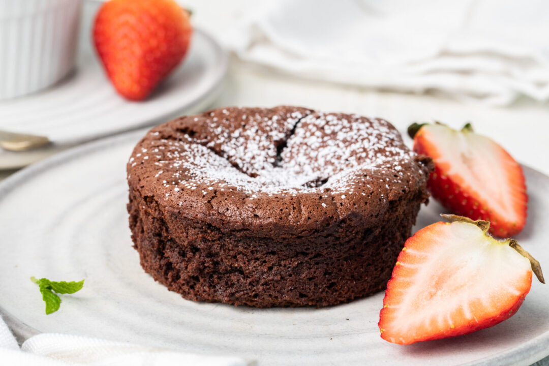 Chocolate soufflé with powdered sugar and strawberries on a serving dish