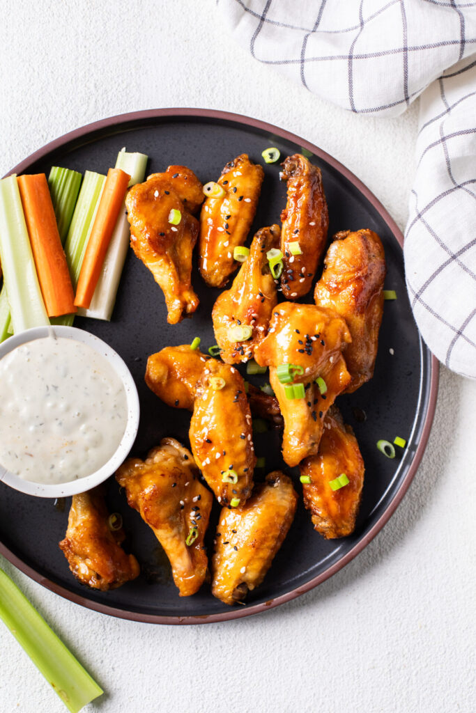 Hot Honey Baked Chicken wings on a plate with celery and carrots 
