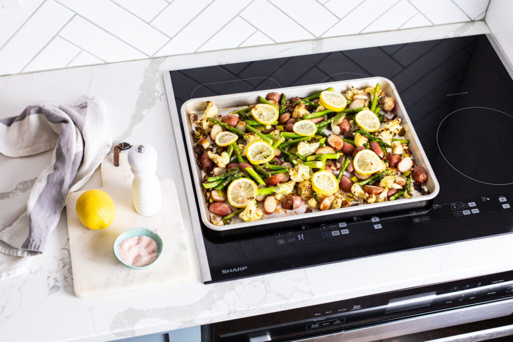 Spring vegetables on a baking sheet on a sharp cooktop
