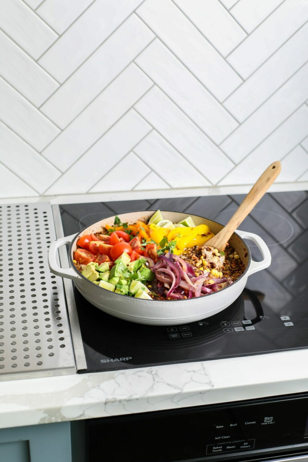 The ingredients for a one-pot Mexican quinoa bowl in a skillet on top of a Sharp 24 in. Induction Cooktop with Side Accessories (SCH2443GB).