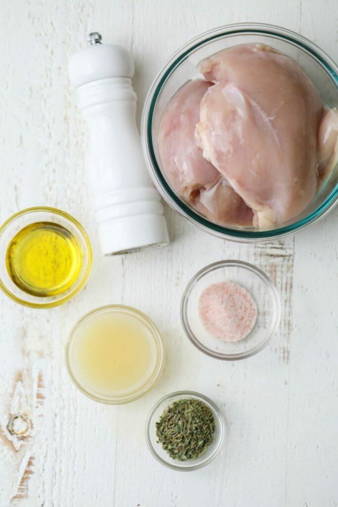 Raw chicken and ingredients for a marinade for Cobb Salad on a white table