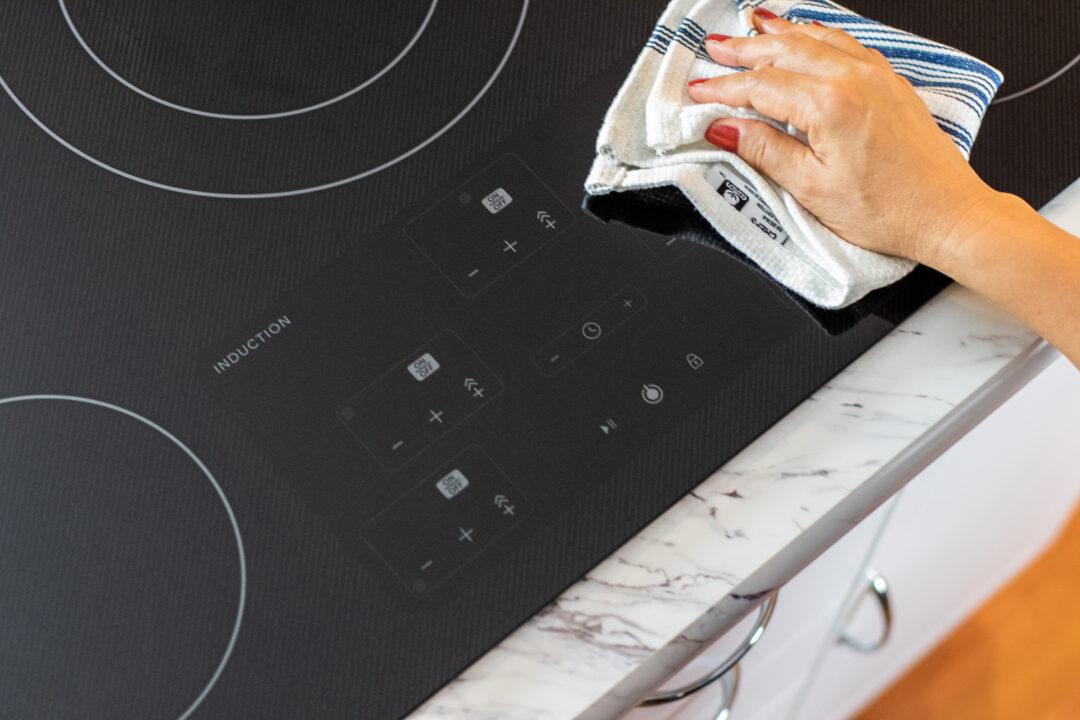person wiping a Sharp induction cooktop
