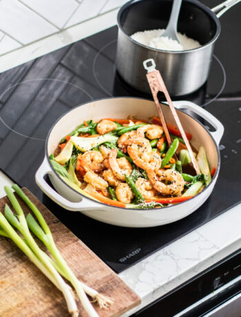 Shrimp and veggie stirfrying cooking in a pan on an induction cooktop