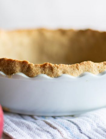 Pie crust in a bowl next to an apple.