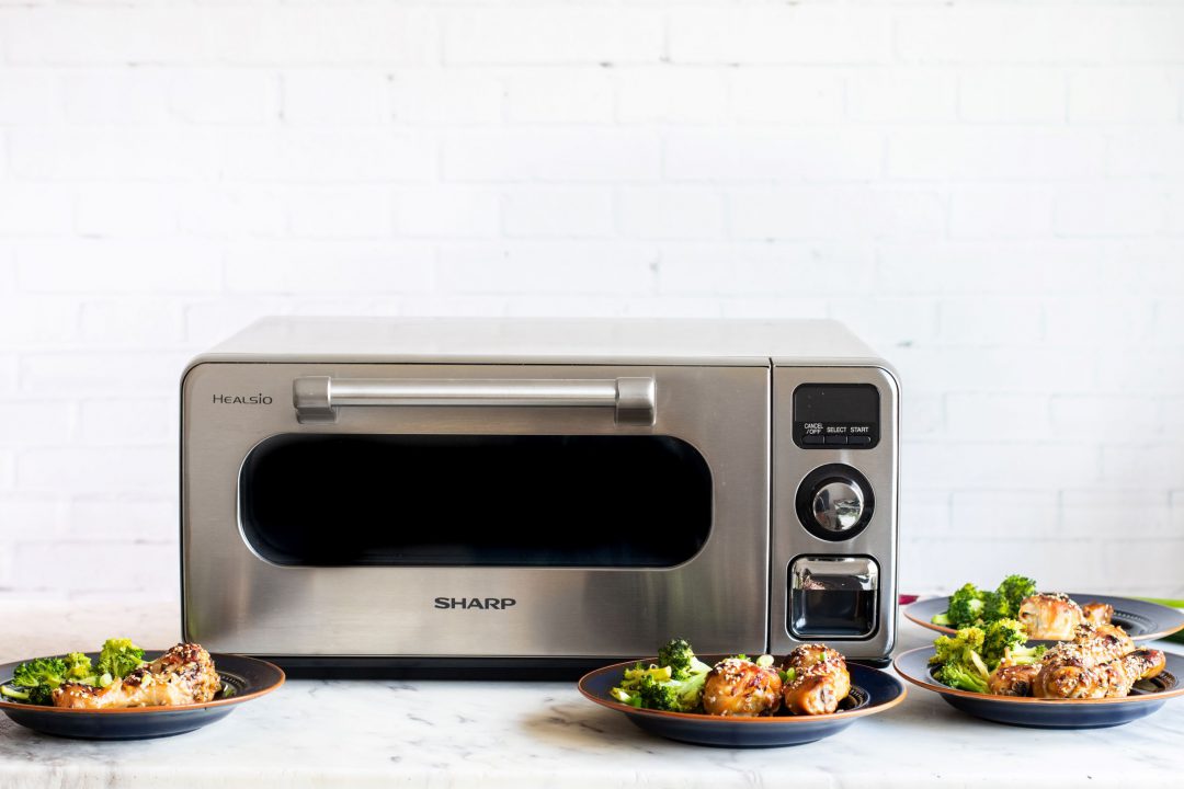 Sharp Superheated Steam Countertop Oven surrounded by plates of food