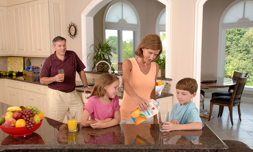 Family of four in a kitchen drinking orange juice