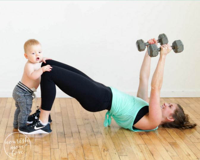 A baby holding mothers knees while mother is working out