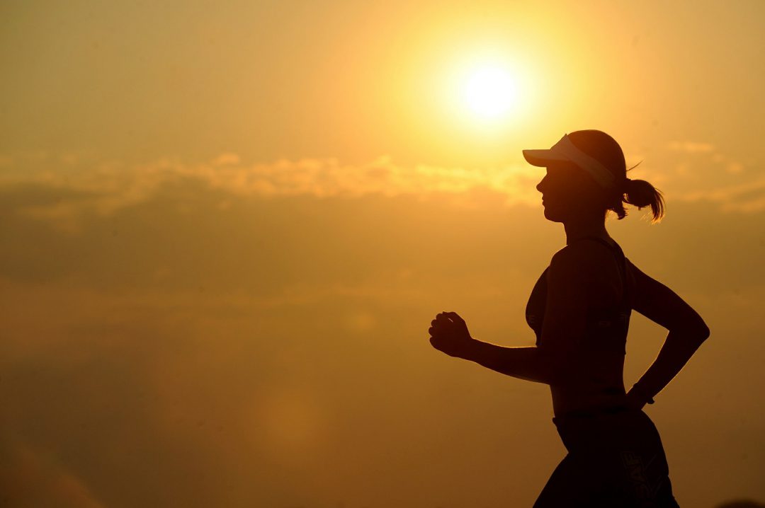 Woman jogging along a sunset
