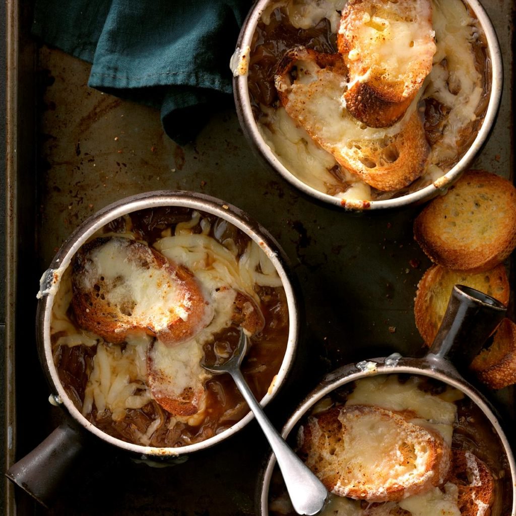 three bowls of french onion soup on a baking pan