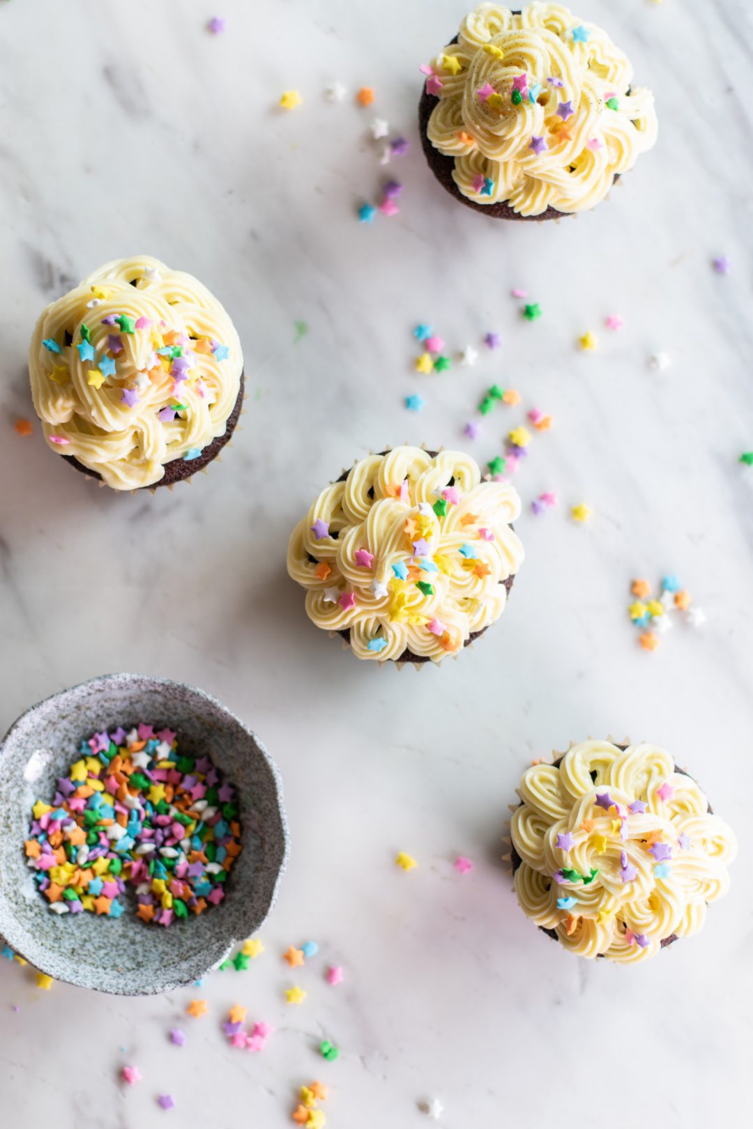 Cupcakes being prepared with sprinkles.