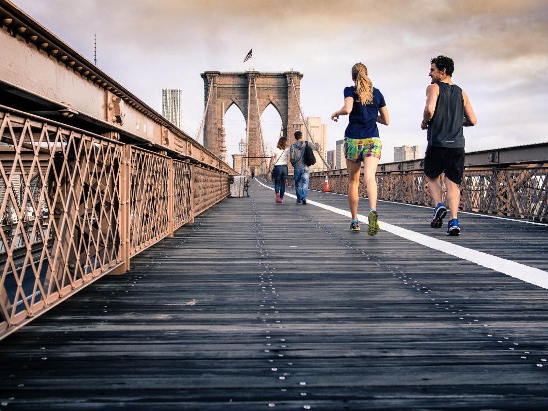 Joggers jogging across Brooklyn Bridge.
