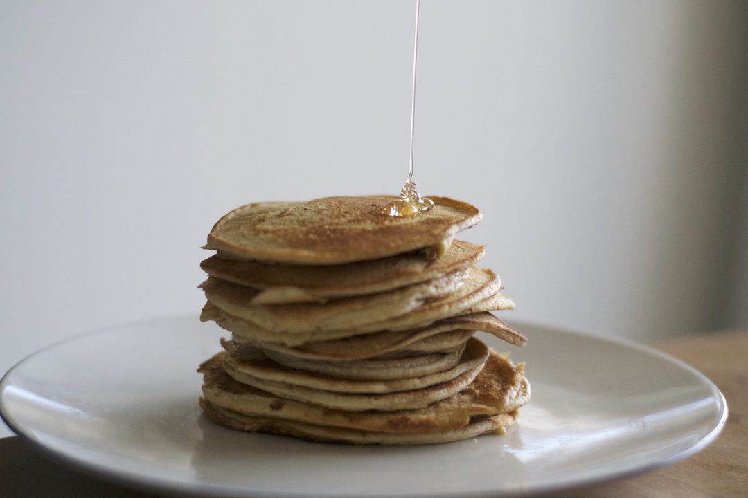 Pancakes being stacked with syrup.