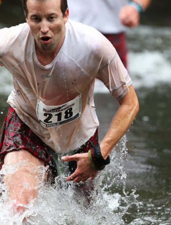 A man coming out of a lake during a marathon.