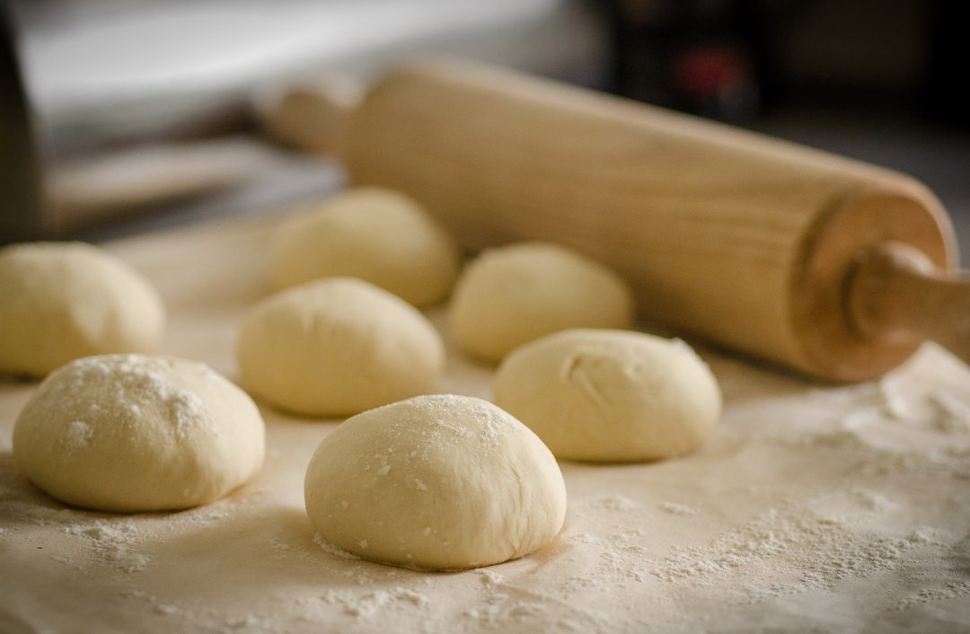 Flour and dough next to a roller.