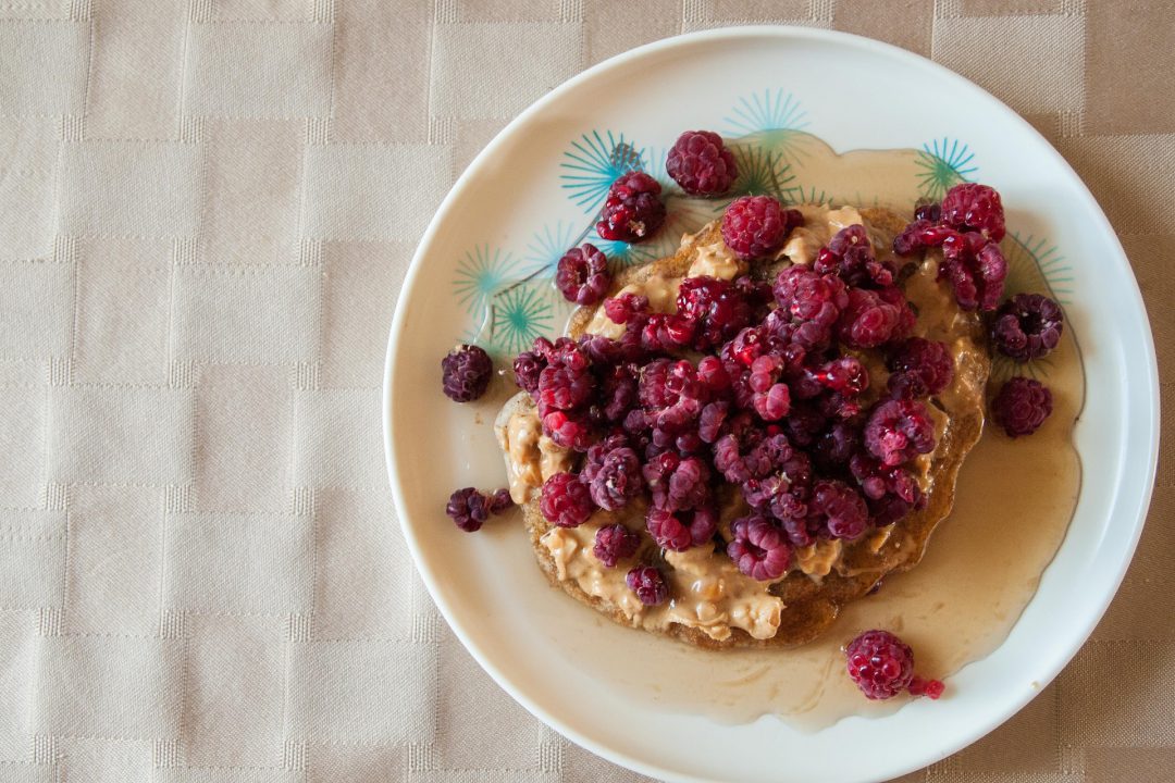 Peanut butter and rasberries on a dish.