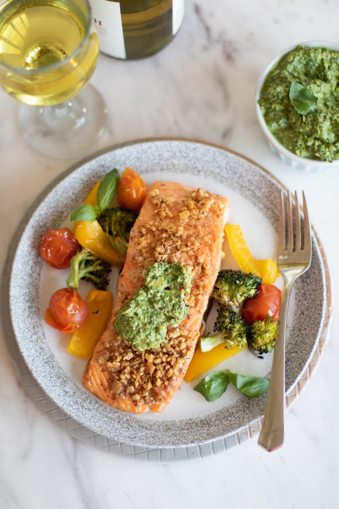 Pesto salmon with vegetables being served.