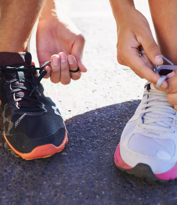 Man and woman tying their shoes preparing for a run.
