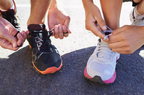 Man and woman tying their shoes preparing for a run.