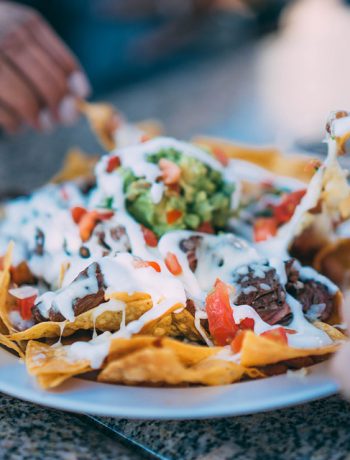 Loaded nachos being shared by a few people.