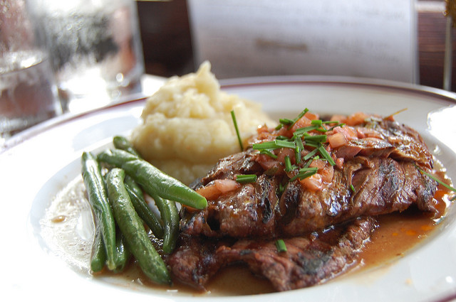 Skirt steak with mashed potatoes being served.