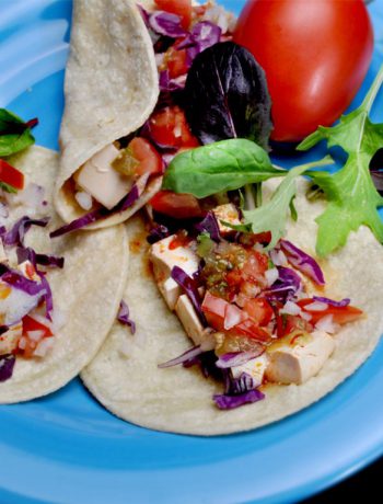 Tacos with onions and tomatoes on a plate.