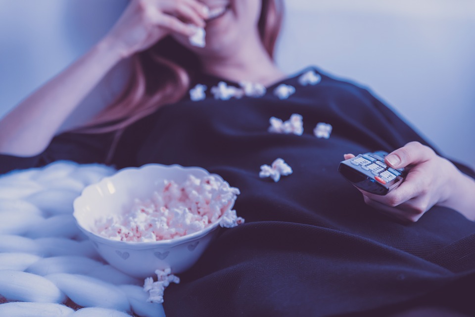 Someone eating popcorn while holding a remote.
