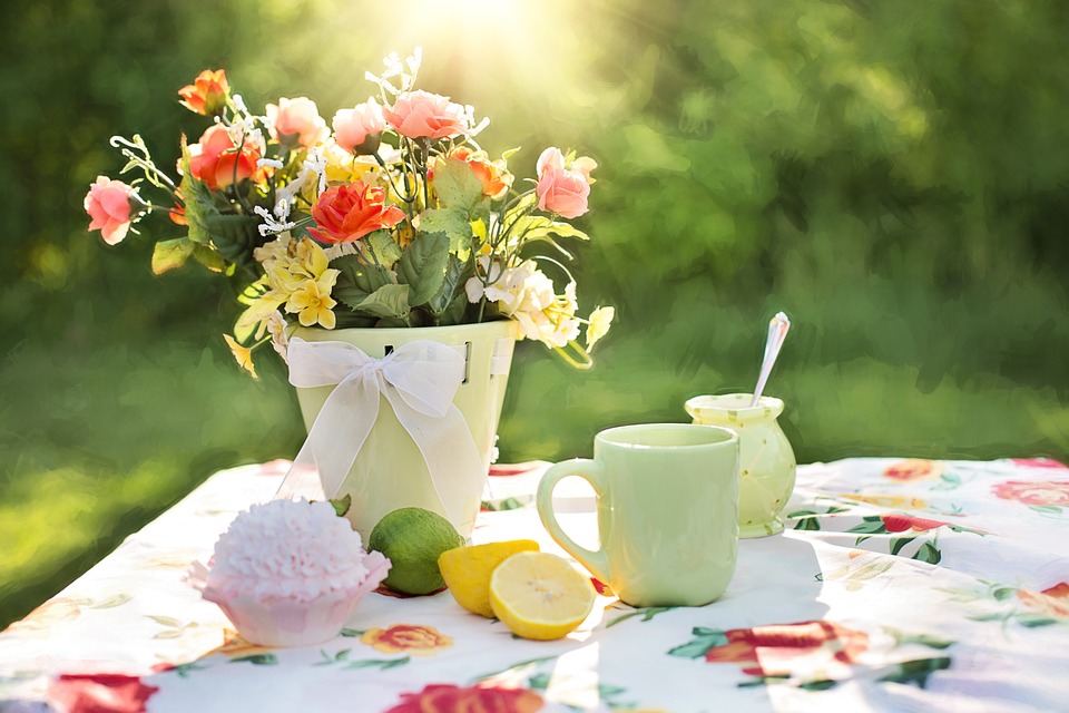 Bouquet of flowers on an outdoor table with coffee cups and lemons.