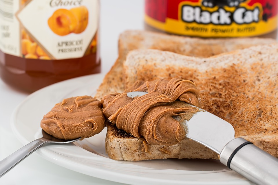 Peanut butter being smeared on a piece of bread.