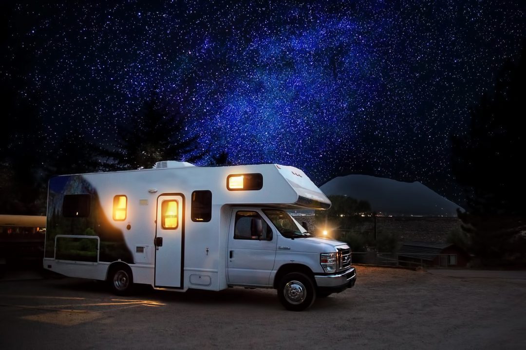 RV in a campsite woth starry sky in the background.