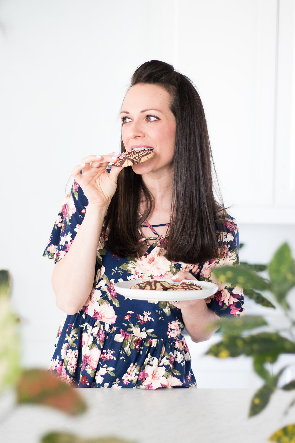 A woman eating cookies with a chocolate drizzle.