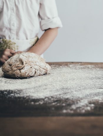 Dough on powder on a cutting board next to a chef.