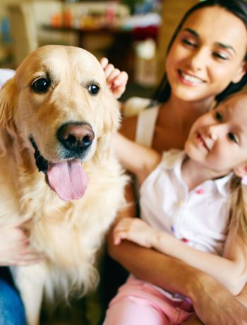 Family of three petting their dog.