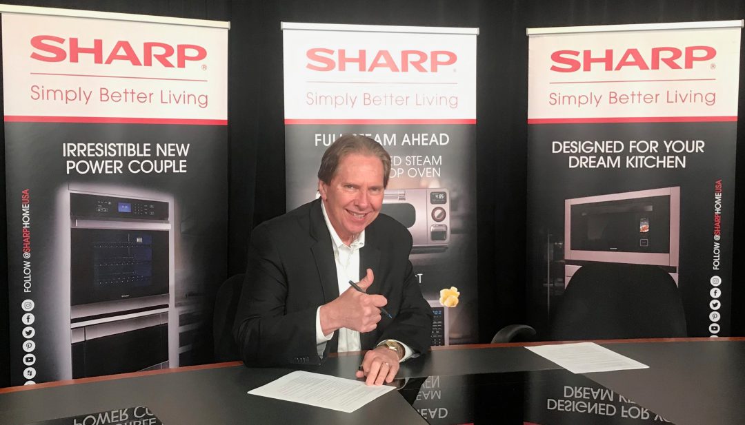 Peter Weedfald signing Nationwide contract with Sharp backdrop.