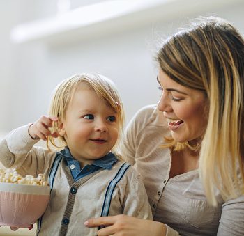 Smiling little boy and his mother eating popcorn.