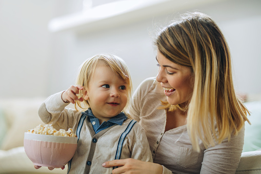 Smiling little boy and his mother eating popcorn.