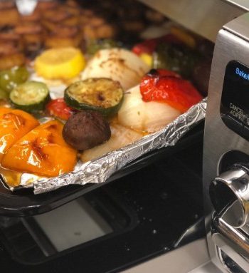 Sheetpan with vegetables entering a Sharp Supersteam Countertop Oven.