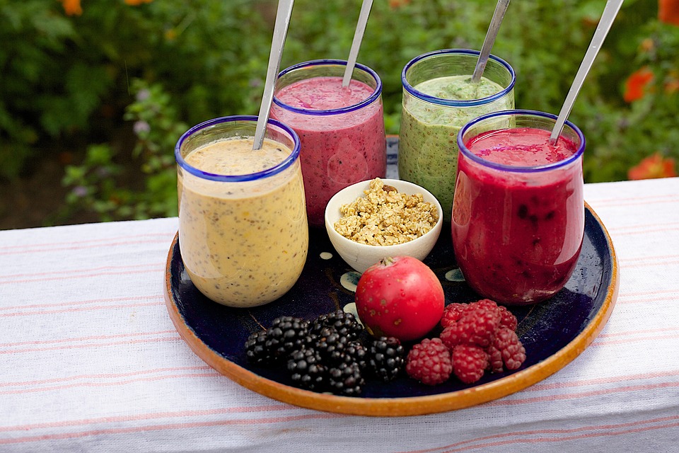 Four smoothie flavors with rasberries on an outdoor tray.