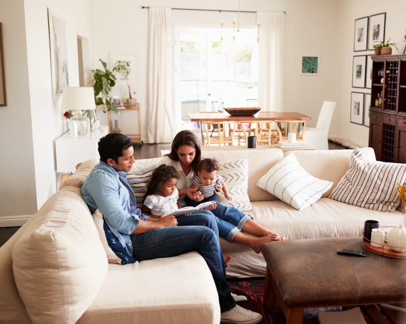 Family of four sitting in a living room with young children.