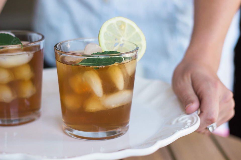 Iced tea with lemon being prepared on a white tray.