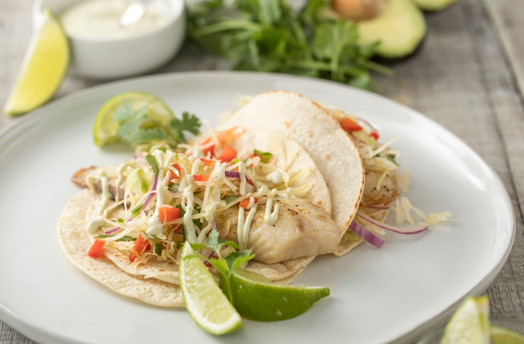 Fish tacos on a plate with lime.