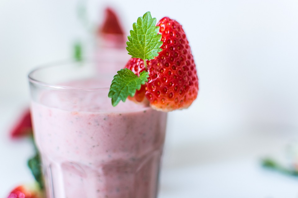 Strawberry smoothie with a strawberry on the rim of the cup.