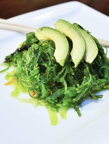 Seaweed Salad on a white plate with chopsticks.