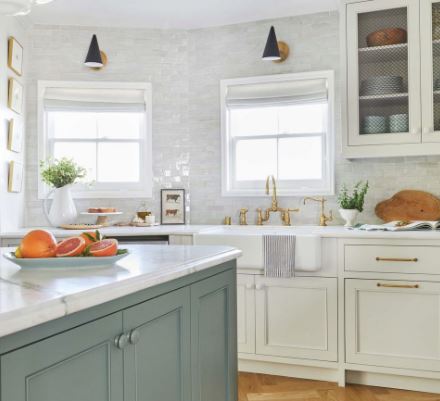 White kitchen design with a blue island and gold hardware.