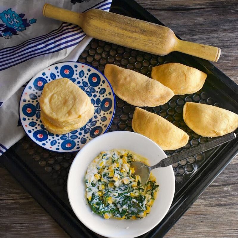 Ricotta Spinach and Corn Empanadas on a tray next to a blue cloth.